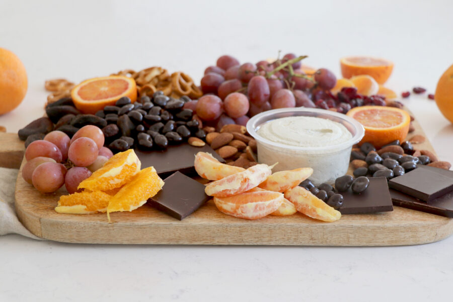 Wooden plank with a variety of fruit, vegan spreads and citrus.