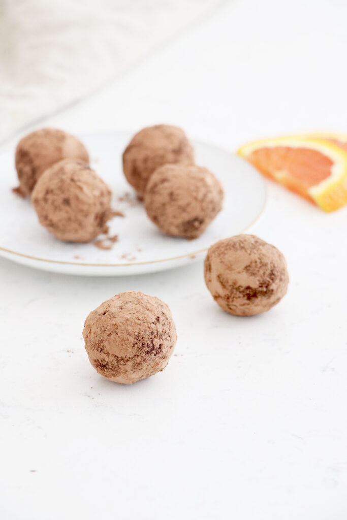 White plate with 4 truffles and 2 in front of the plate.