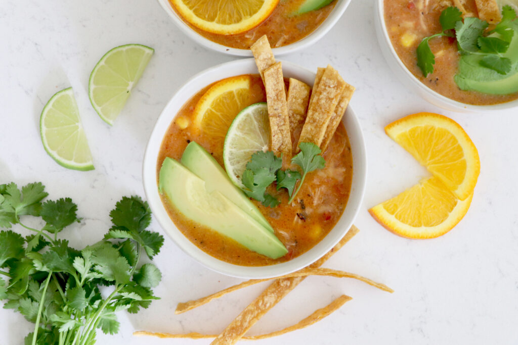 white bowls with nacho soup surrounded by veggies.