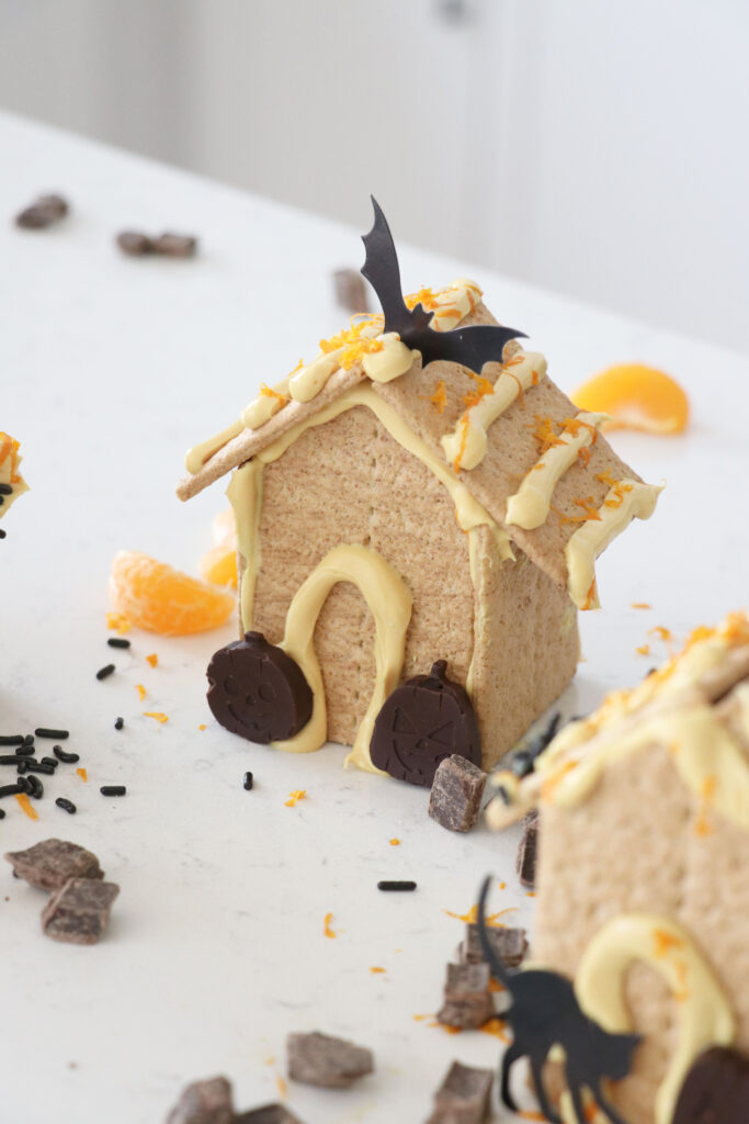 Graham cracker haunted houses with frosting, chocolate pumpkins and decorations.