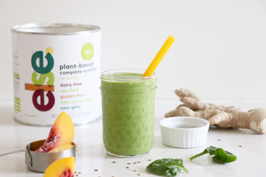 Green smoothie with yellow straw and container of complete nutrition for kids.