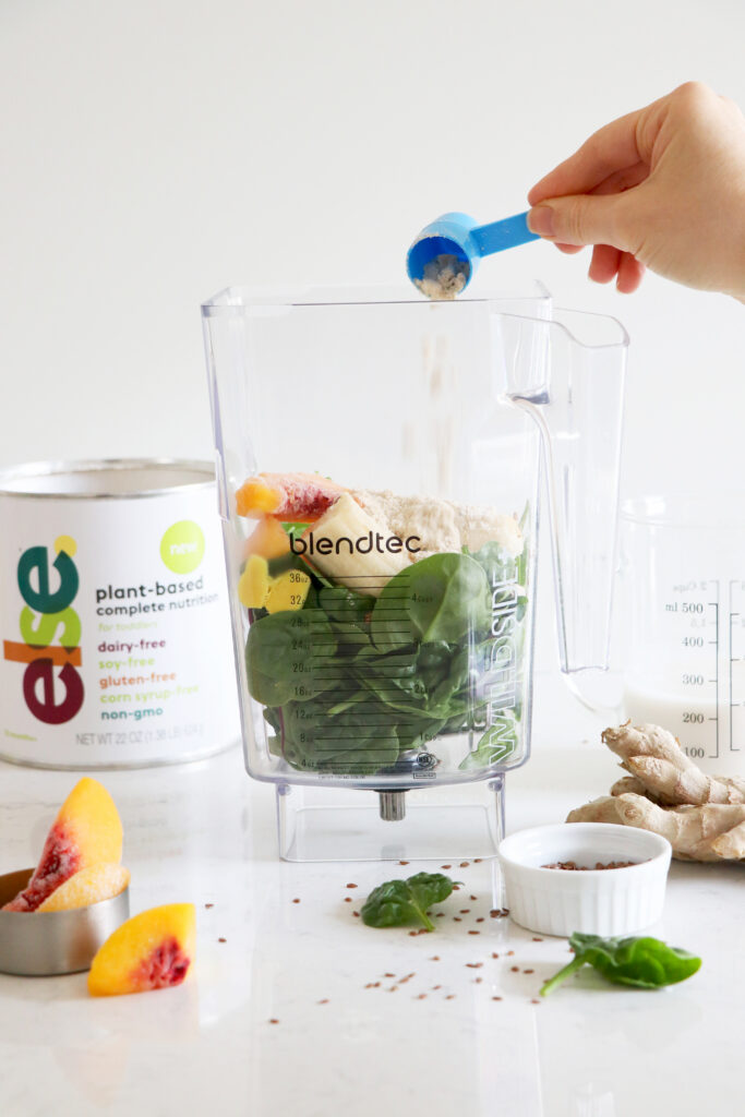 Blender with fruits and veggies and Else nutrition container.