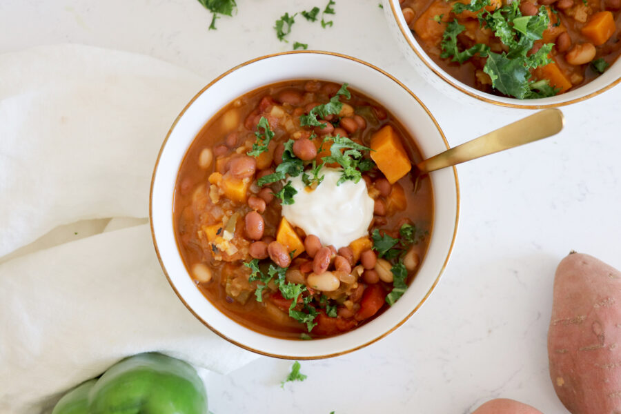White bowl with chili. Gold spoon inside.
