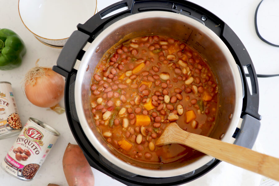 Open instant pot filled with chili. S&W Bean cans next to instant pot.