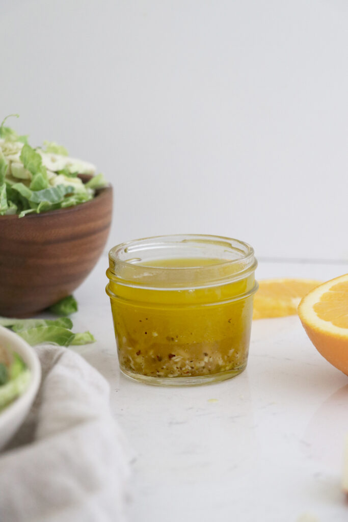 Container of dressing with salad on the side.