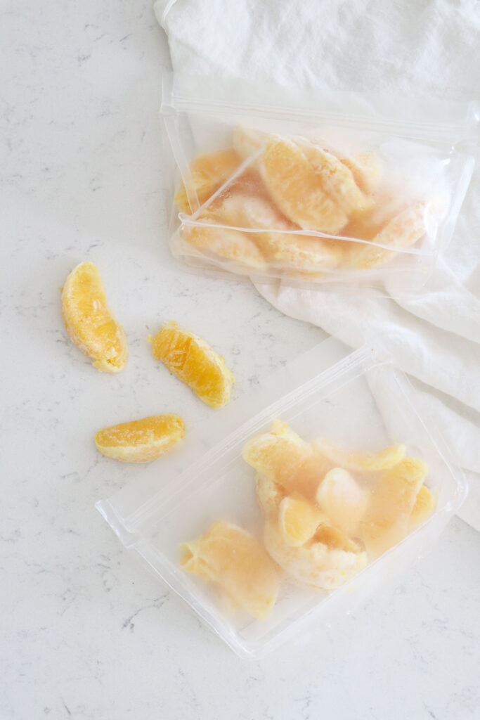 Clear bags of frozen orange slices and a few on the table.