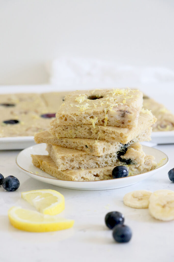 White plate with sliced pancakes and sheet pan in background.