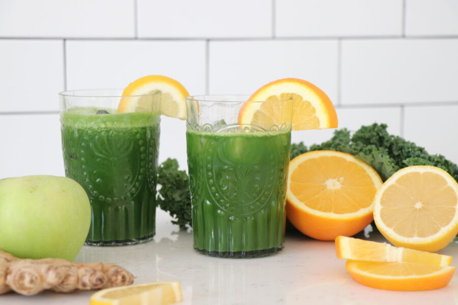 Two glasses of green juice with sliced orange.
