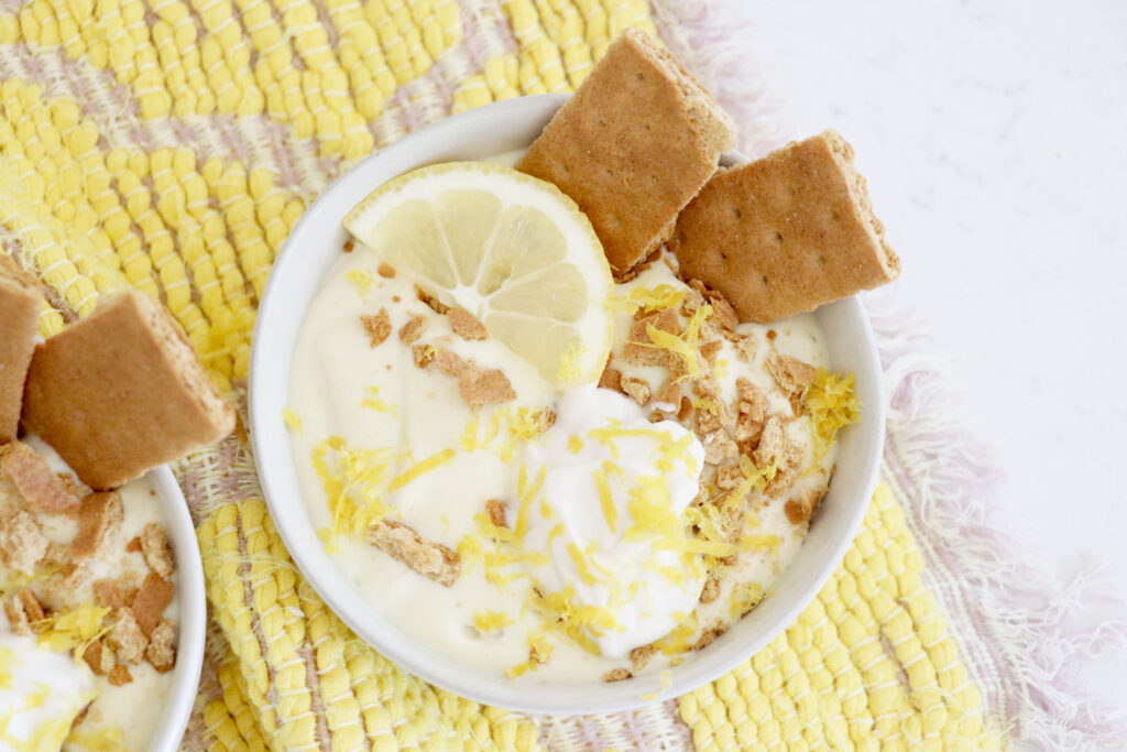 Birds eye view of smoothie bowl that has lemon slice on top, graham crackers stuck on the side and lemon zest on top.