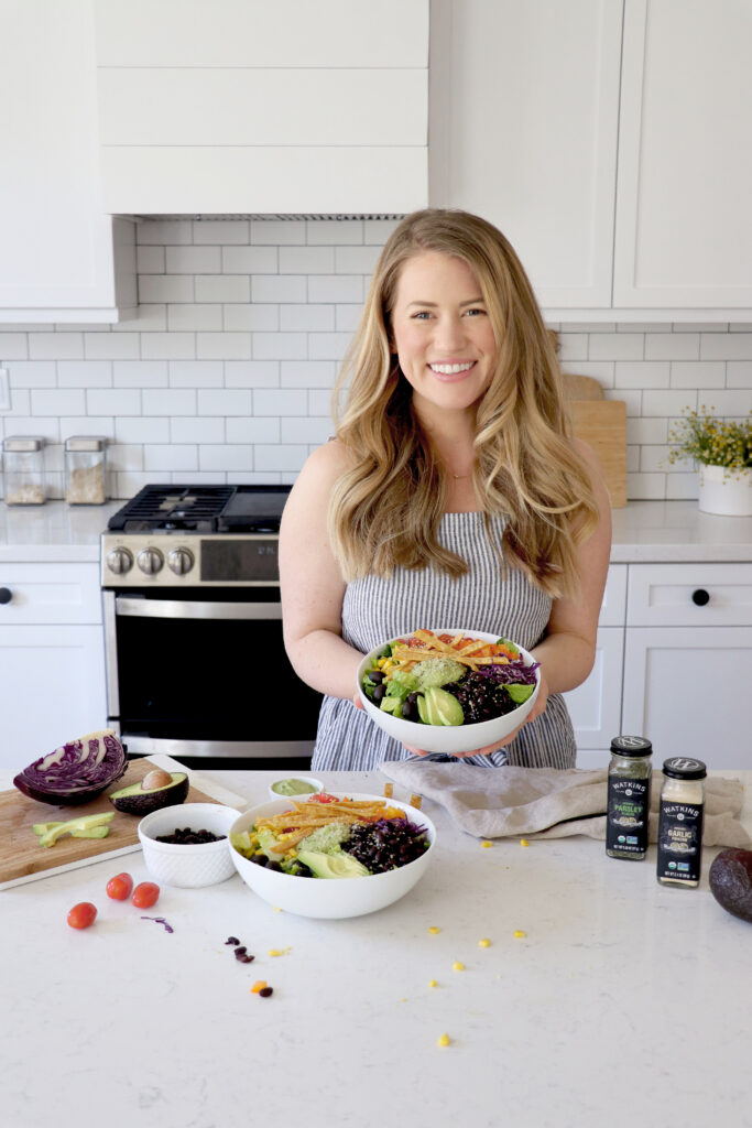 Megan holding taco salad bowls in kitchen.