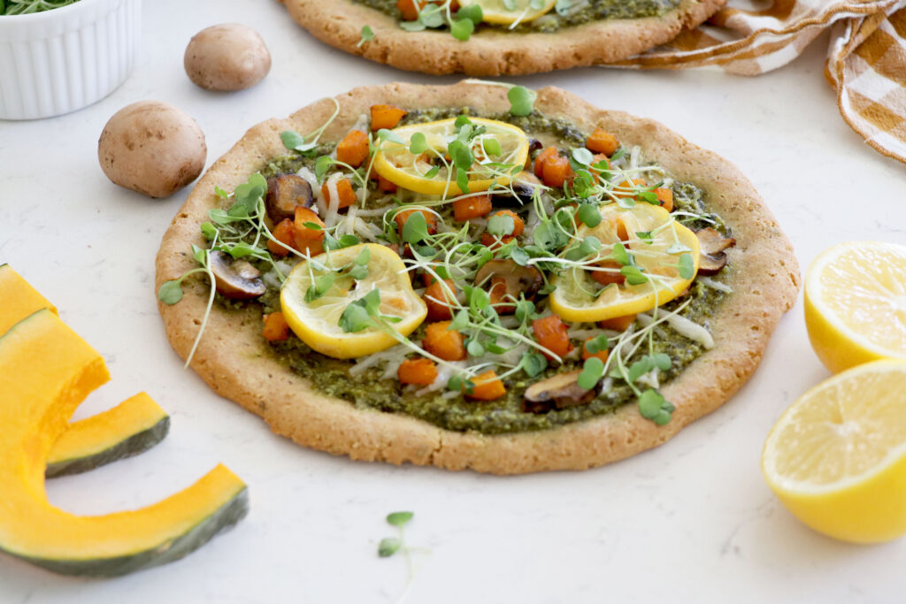 pizza with pesto, veggies and roasted lemon slices on top.