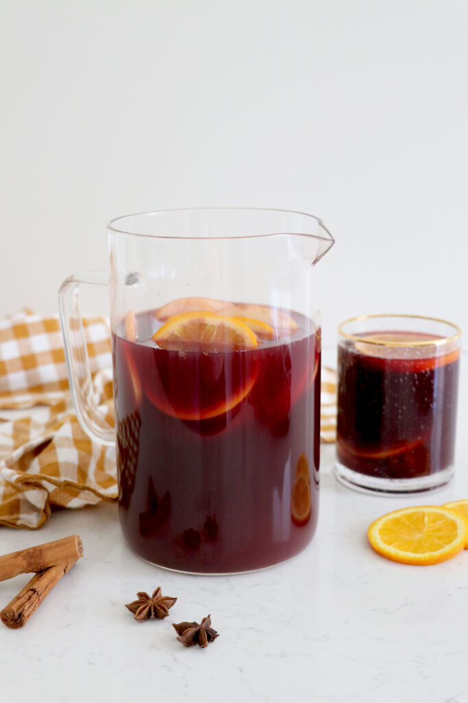 Glass and drink pitcher with orange apple sangria.