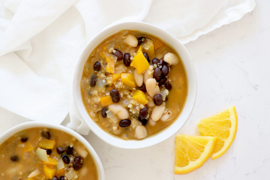White bowls with chili and orange slices on the side.