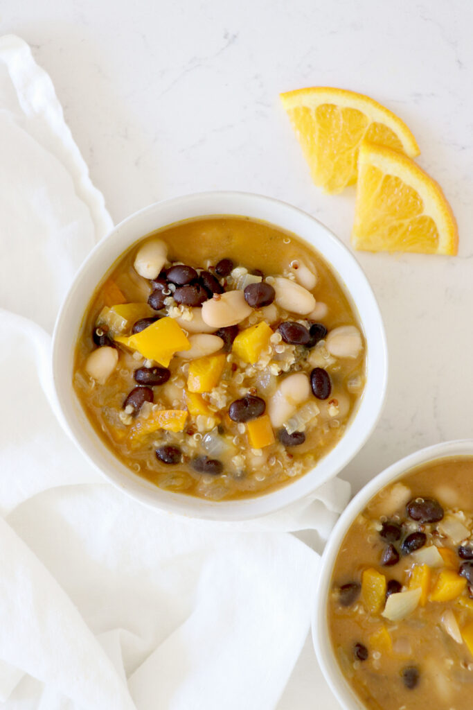 Two white bowls with chili and orange slices on top right hand side.