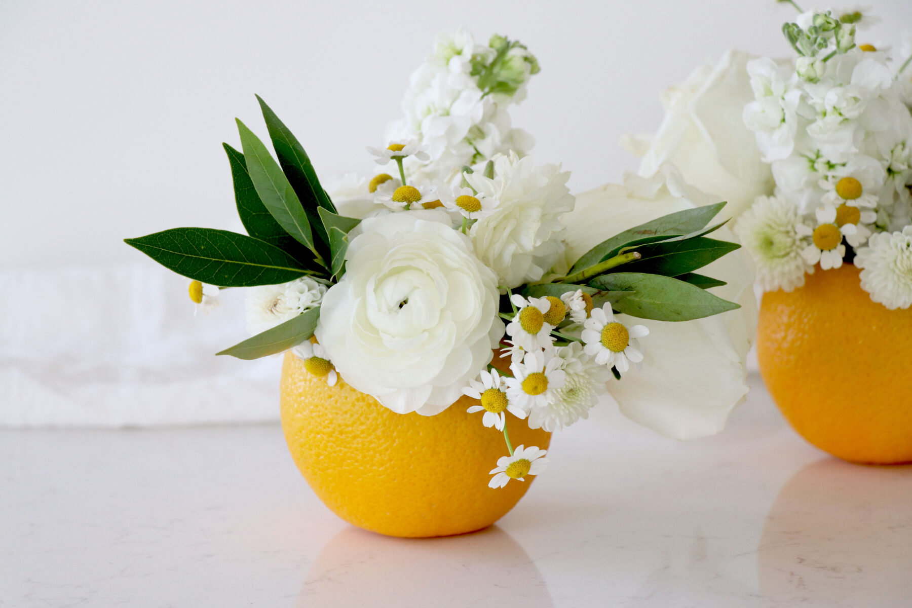Orange vase with white florals and greenery.