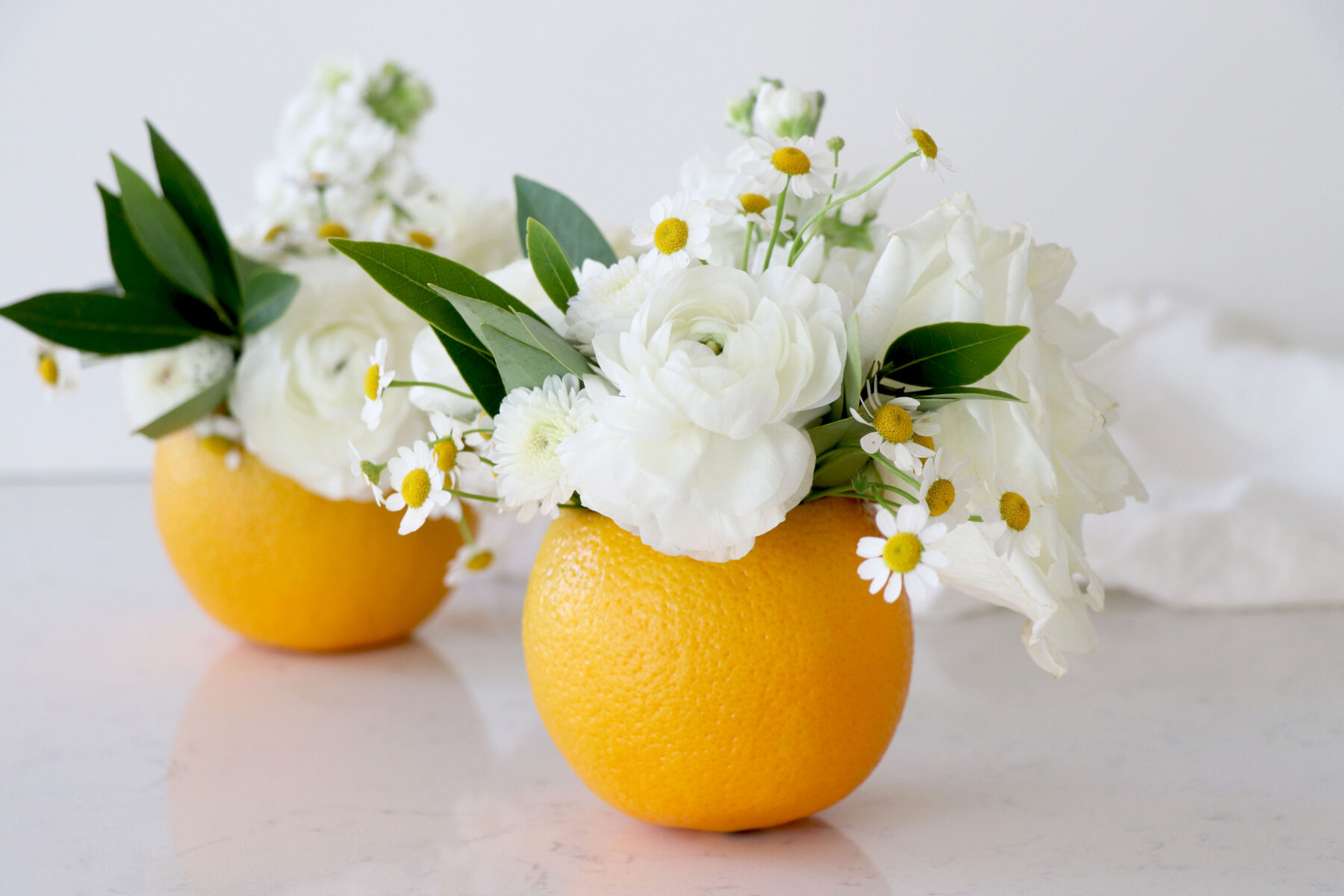 Two oranges with floral flowers and greenery.