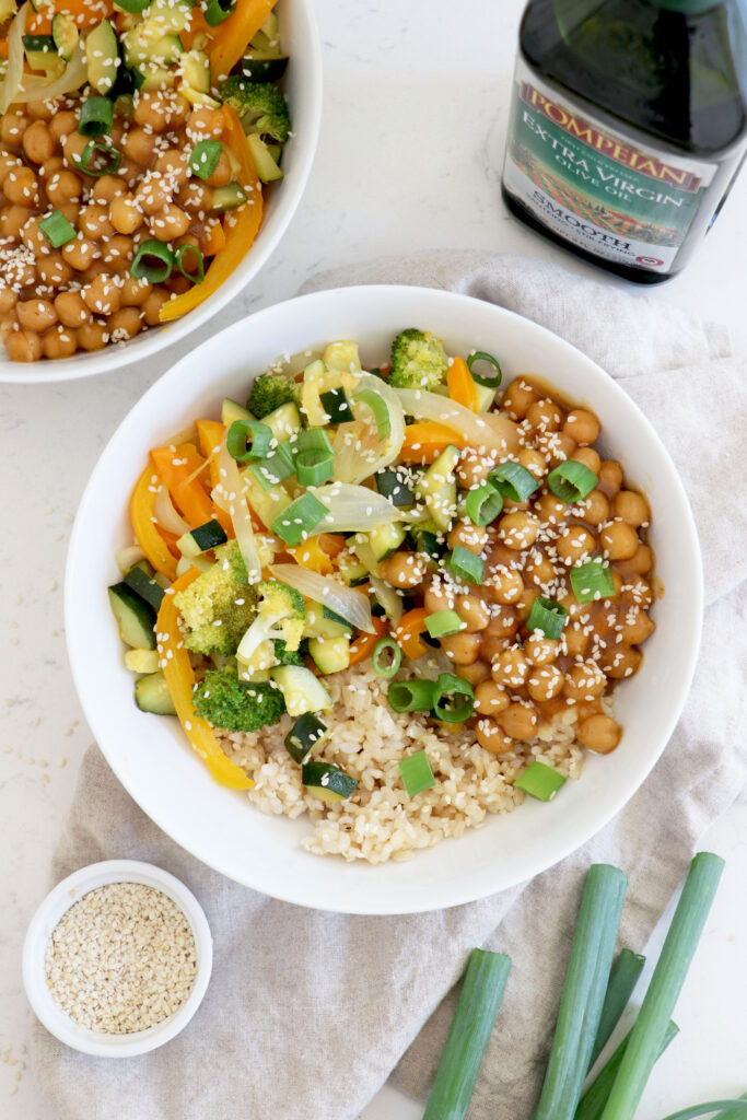 Orange Ginger Stir Fry in white bowls with bottle of olive oil on the side.