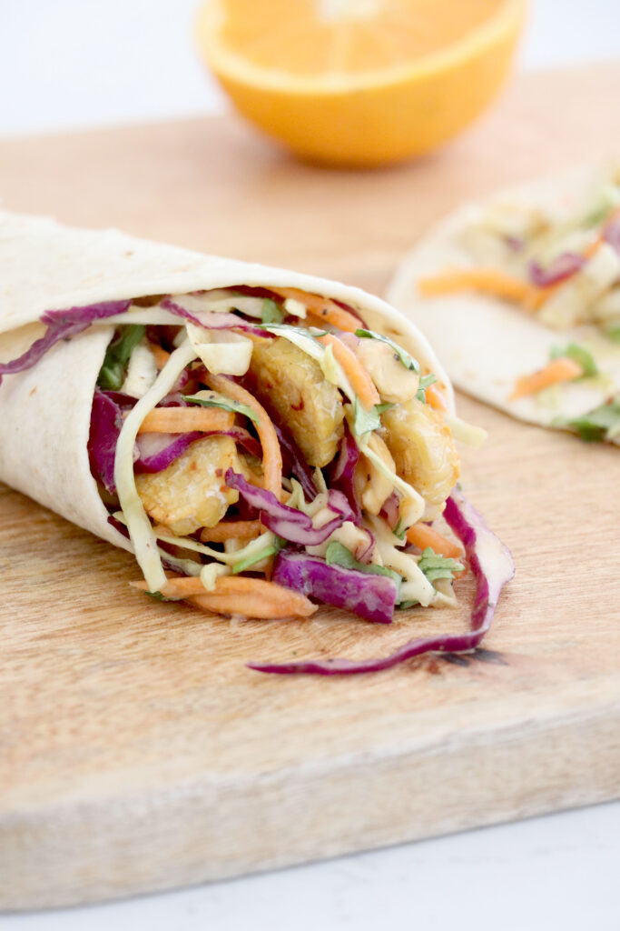 Peanut wraps on a wooden board with crunchy cabbage slaw.