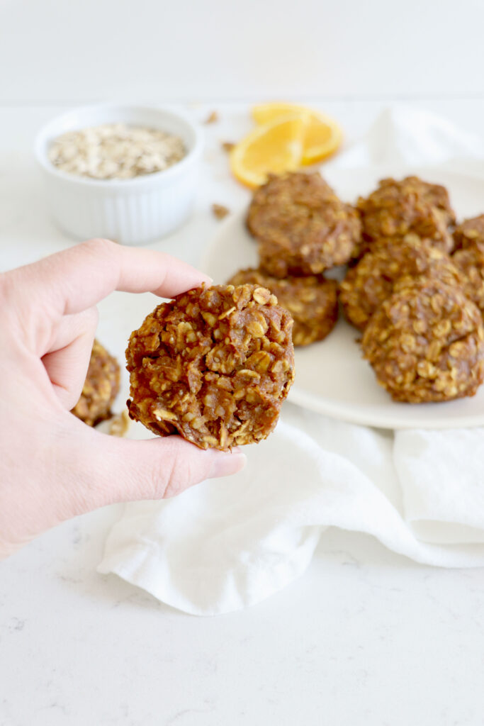 Hand holding oatmeal cookie with cookies in background.