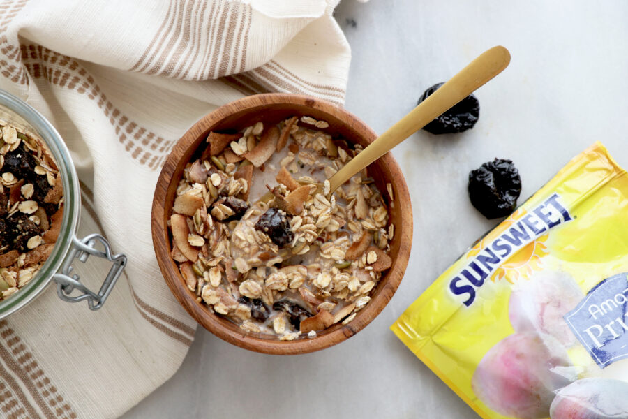 Bowl of muesli with spoon inside and Sunsweet package on there side.