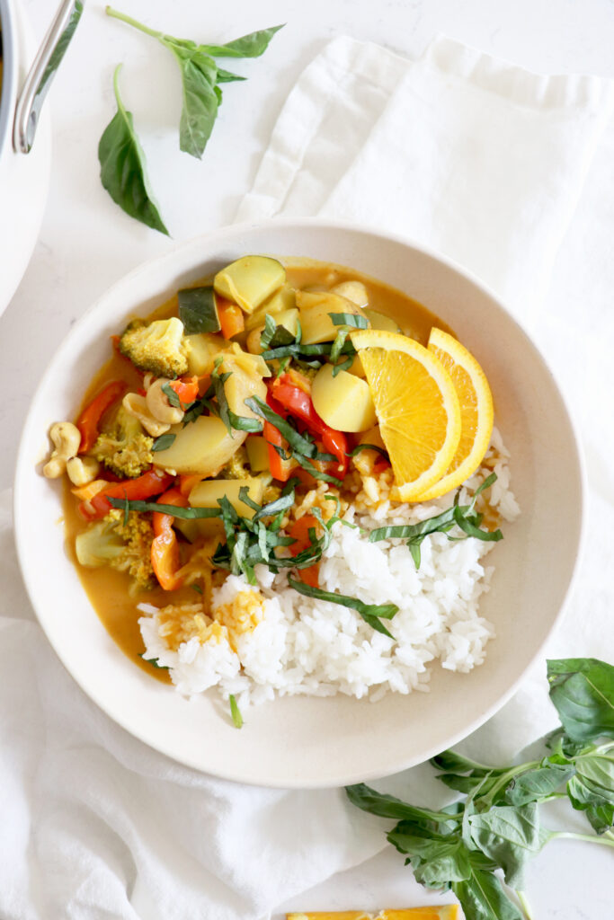 White bowl filled with vegetable curry and white rice.