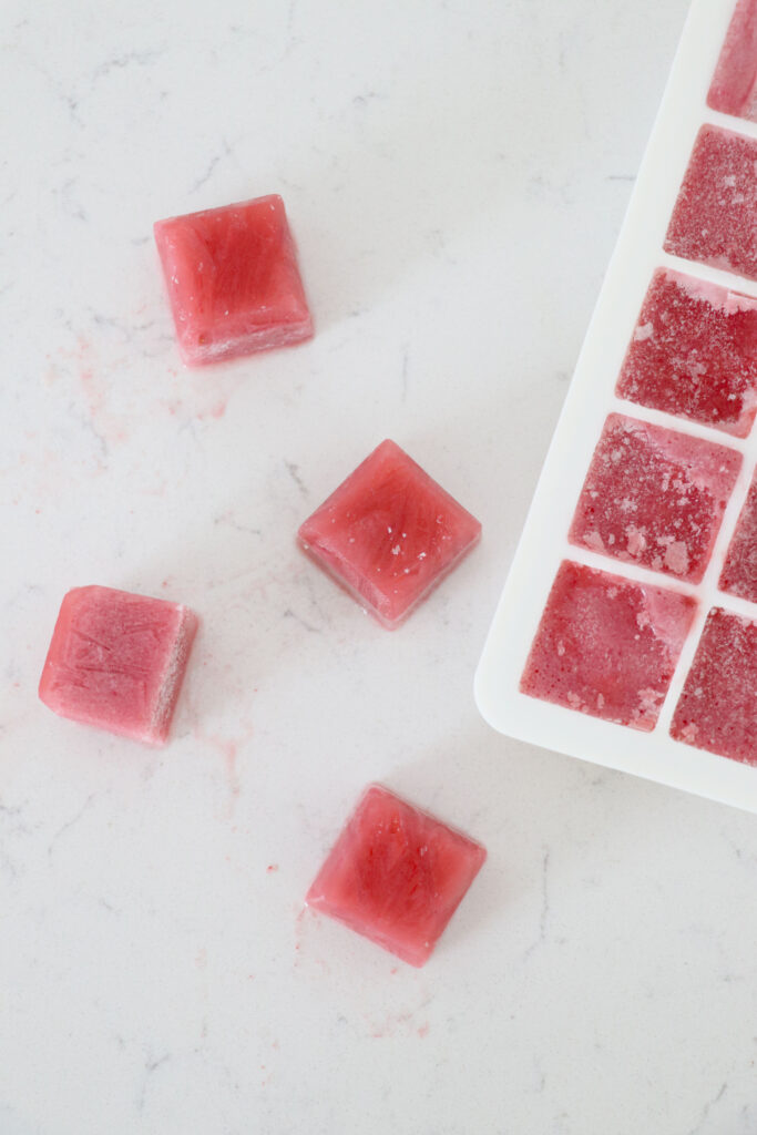 Tray of smoothie cubes with some on the left side on the counter.