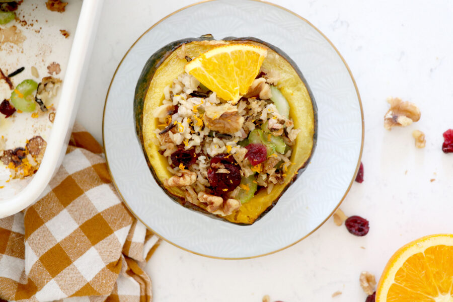 White plate with stuffed acorn squash and dish on the left.