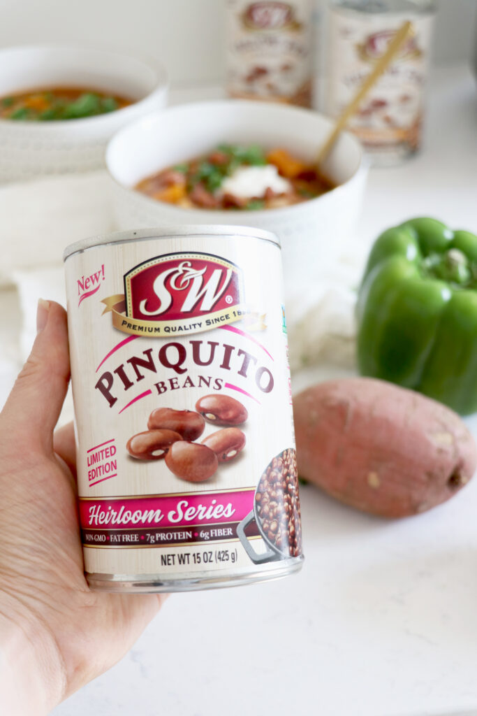 Holding a can of S&W Beans with chili in the background.