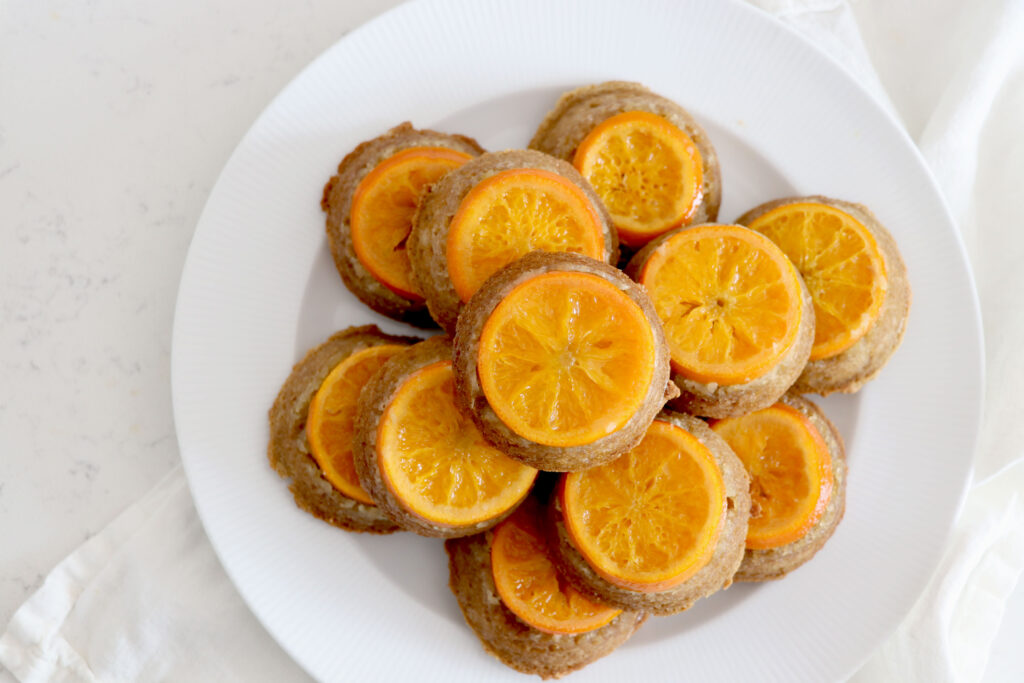 Round platter stacked high with orange upside down mini cakes
